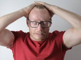 this image shows a desperate man wearing glasses and putting his two hands over his head