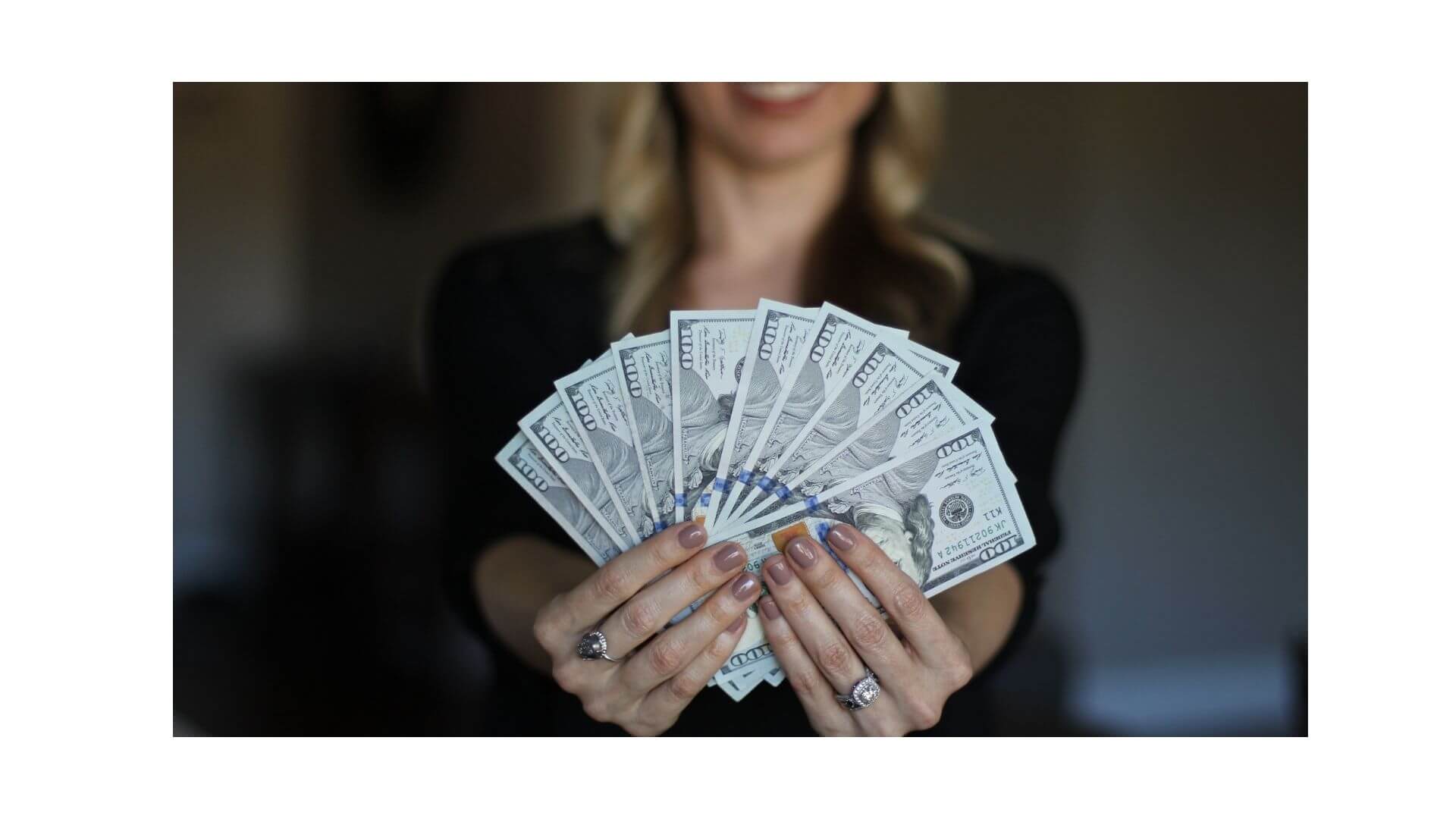 A woman standing and showing a lot of dollar notes